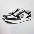 Black-and-white low-top sneakers with white laces, a triangular side plaque, and a white midsole.