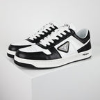 Black-and-white low-top sneakers with white laces, a triangular side plaque, and a white midsole.